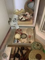 Shelf view of assorted ashtrays, several smoking pipes, collectible tins and matchbooks in a box and large yellow glass ashtray above