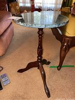 Full view of side table showing round stone top and three-legged wooden base in living room setting.