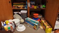 View of food storage containers, polythene rolls, plastic bags, and other items inside cabinet