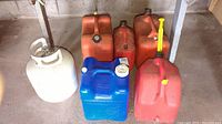 Front view showing four jerry cans, one propane tank, and one blue water jug arranged on the ground