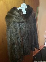 Front view of dark brown mink jacket on hanger showing shawl collar and fur texture.