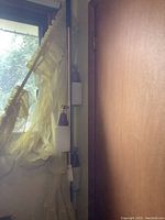 Retro adjustable floor to ceiling pole lamp mounted near window and door with white textured glass shades and brass pole.