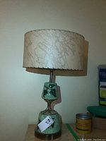 Full view of the retro ceramic and metal table lamp with original cream fabric shade featuring abstract muted line design