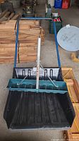Top view of Garan metal handled resin snow shovel showing black scoop and blue metal handle with silver brace