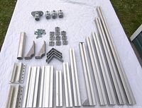 Top view of all aluminum extrusion pieces laid out with brackets, bolts, plates, and Kee Klamps on a white cloth background.