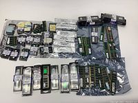 Wide view showing assortment of RAM sticks and packages laid out in rows on a white surface.