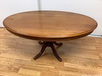 Full top view of oval wooden coffee table on wooden floor.