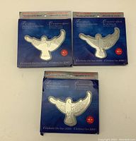 Three official Millennium Keepsake stamps with dove-shaped silver presentation holders in blue packaging celebrating the Year 2000.