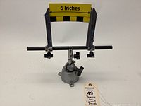 Panavise base with adjustable holder and a yellow measuring strip indicating 6 inches width between the clamps, with the lot tag in front.