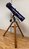 Full view of blue optical tube on wooden tripod with EQ-2 mount