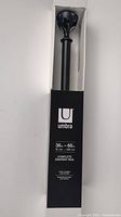 Boxed Umbra drapery rod in black, showing rod length and branding on packaging.