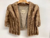 Front view of vintage mink stole hanging, showing fur texture and satin lining with brand label reading 'Leryne Furs'.