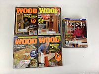 Four Wood magazines and a small stack of assorted woodworking magazines showing titles and covers.