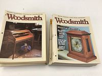 Two stacks of Woodsmith magazines showing covers with woodworking projects including a roll-top desk and mantle clock.