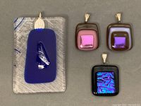 All four Murano glass pendants displayed together on a grey background showing different colors and shapes