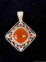 Square pendant with polished cornelian center and red tourmaline stones in silver frame