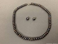 Necklace and earrings laid flat on neutral background