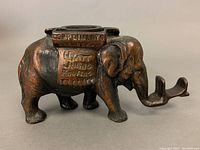 Side view of vintage cast iron elephant ashtray advertising Hyatt Jumbo Premium Cigarettes, showing copper finish and detailed elephant features.