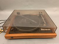 Full front view of the turntable with closed, visibly scratched and dusty dust cover showing the Dual badge on front wooden panel.