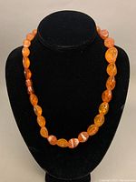 Full view of the amber necklace on a black display bust showing bead size and color variation.
