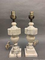 Pair of vintage white marble table lamps on gray background showing front and cord.