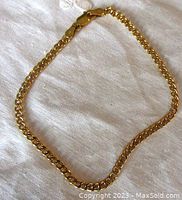 Full view of the yellow gold curb link bracelet laid flat on fabric