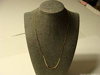 Full length necklace displayed on a bust showing flat herringbone style