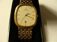 Front view of Eterna watch face showing diamond dust dial, gold-tone markers and hands, date window.