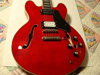 Front view showing red gloss top, dual zebra pickups, F-holes, controls