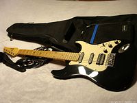 Full view of black Rocker electric guitar RG-100 with cable, showing body, maple neck and headstock, and included soft case.
