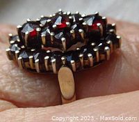 Close-up view of ring with deep red oval-shaped garnet cluster set in silver with prong mounts.