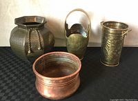 All four planters and vases shown on black checkered fabric background, front facing view.