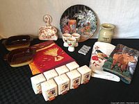 Full lot including spice jars, egg cups, utensils jug, casserole dishes, tablecloth and placemats arranged on black surface.