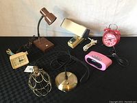 Full view of all lamps and clocks showing the full lot contents on black surface.