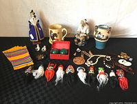 Overview of all items including bird figurines, mugs, napkins, healing balls, doll, Mudmen figurines, and masks.