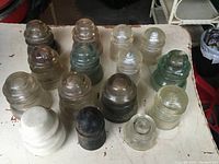15 glass insulators arranged on a table showing various colors and shapes