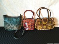 All three purses: green embossed leather crossbody, small brown woven leather handbag, and brown geometric pattern handbag