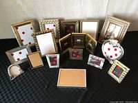 Perspective view of the entire lot showing all frames arranged standing and lying down, featuring multiple gold and silver metal frames with varied designs and sizes.