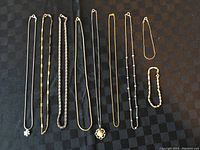 Overview of all necklaces and bracelets on black checkered background