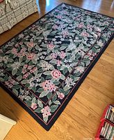 Full view of the floral hand-hooked wool area rug on hardwood floor, showing pattern and border details.