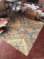 Full view of wool area rug on floor surrounded by boxes and a foldable table.