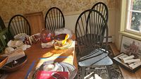 Four black painted wooden spindle-back chairs grouped with other household items on a table and floor, showing overall condition and style.