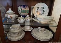 Vintage Syracuse China set arranged on wooden shelves with a variety of plates, cups, sugar bowl, creamer, and vase, showing condition and scale of pieces
