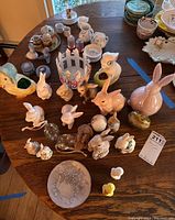 Multiple ceramic Easter-themed figurines including rabbits and ducks, child's tea set items, and a Wedgwood keepsake box on table.