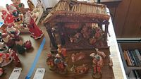 Wide view of the nativity set showing the manger and various figurines set on a table.