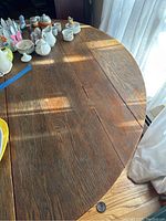 Close-up of round wooden table surface showing scratches and wood grain.