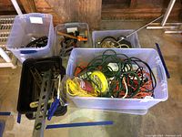 Bins containing extension cords, hand tools, and lighting items in a workshop environment