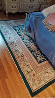 Full view of the floral designed area rug placed under furniture on a hardwood floor showing the entire pattern and condition.