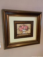 Close photo of the framed floral print showing the double frame, the flower arrangement, and the condition of the outer frame including scratches and chip at left corner.
