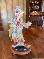 Front angled view of clown figurine with banjo on wood table